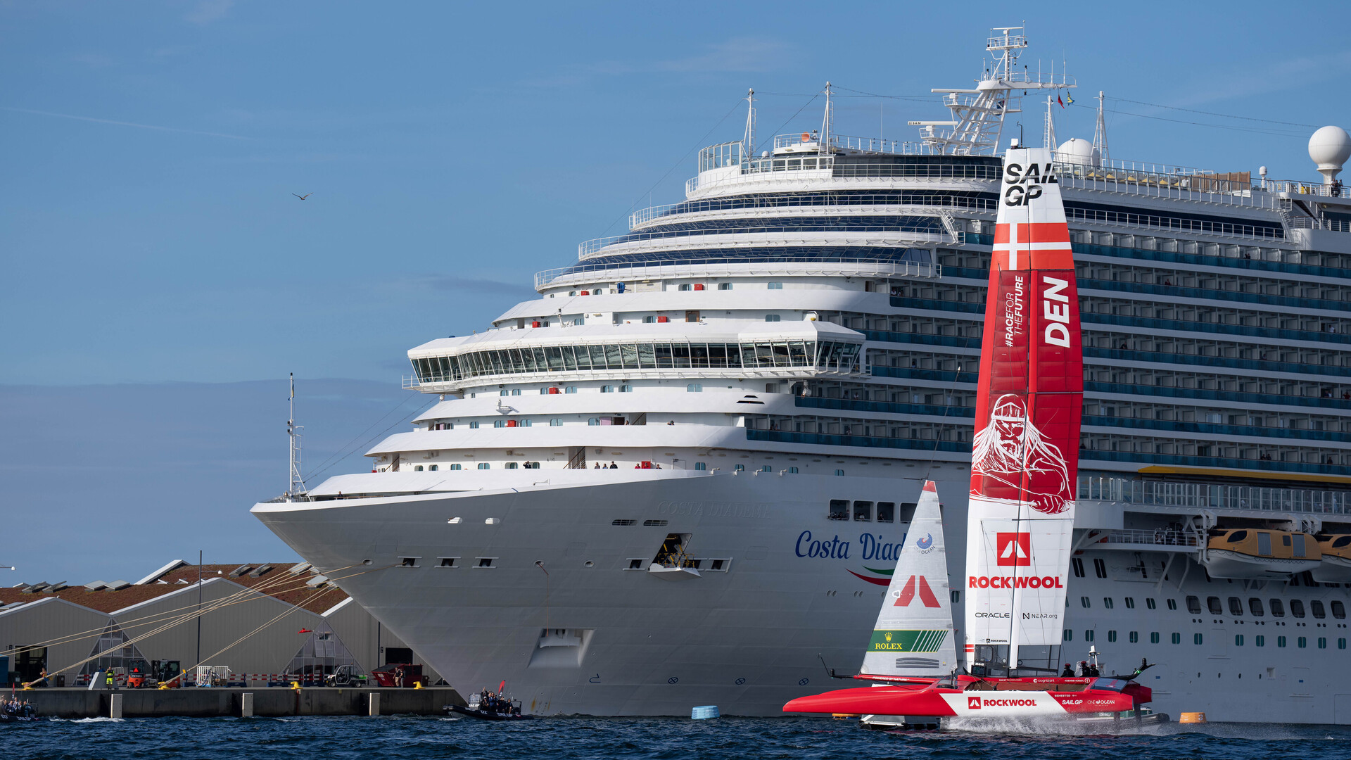 The Denmark SailGP Team's F50 in Copenhagen sailing next to a cruise ship. The wing shown is the medium-sized wing with a height of 24m.